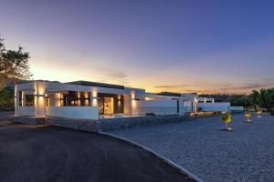 ein großes weißes Haus mit Sonnenuntergang im Hintergrund in der Unterkunft Armonia Suites in Gennadi