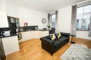 ein Wohnzimmer mit einem schwarzen Sofa und einer Küche in der Unterkunft Parkhill Luxury Serviced Apartments - City Centre Apartments in Aberdeen