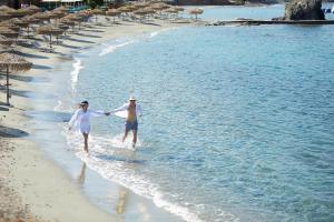 two people walking on the beach in the water at Vincci EverEden in Anavyssos