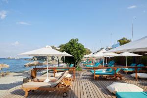 a row of lounge chairs and umbrellas on a beach at Vincci EverEden in Anavyssos