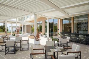 a restaurant with tables and chairs and a bar at Vincci EverEden in Anavyssos