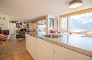 a kitchen with a sink and a large window at Salis 06 by Arosa Holiday in Arosa