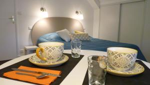 uma mesa com duas chávenas e pratos com uma cama em LES PETITS JARDINS em Marcillac-Vallon
