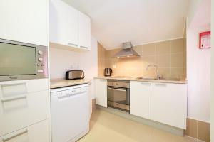 a kitchen with white cabinets and a flat screen tv at Sintra Bliss A Part in Sintra