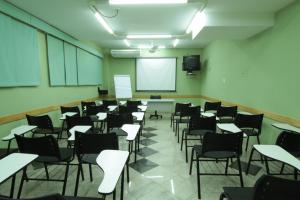 an empty classroom with desks and chairs and a screen at Hotel Malibu in São Carlos