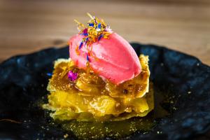 a dessert on a black plate with a pink ice cream on top at Hotel Naudi Boutique Adults only in Soldeu