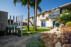 a building with palm trees in front of it at Villa Teocrito Piscina & Mare in Avola