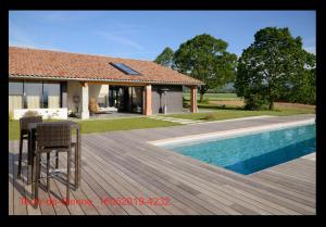 a house with a wooden deck next to a swimming pool at Terre de Sienne in Charpey