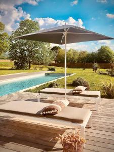 ein großer Regenschirm auf einem Deck neben einem Pool in der Unterkunft Terre de Sienne in Charpey