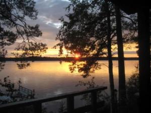a sunset over a body of water with trees at Holiday Home Lähesniemi by Interhome in Hokkanen
