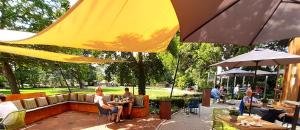 een groep mensen die aan tafels onder parasols zitten bij Hotel De Villa in Dongen