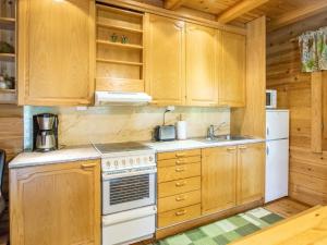 La cuisine est équipée d'armoires en bois, d'une cuisinière et d'un réfrigérateur. dans l'établissement Holiday Home Meritähti by Interhome, à Heinjoki