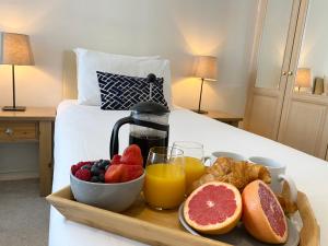 a breakfast tray with fruit and juice on a bed at Apartment next to Victoria Station in London