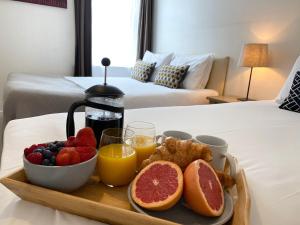 a breakfast tray with fruit and juice on a bed at Apartment next to Victoria Station in London