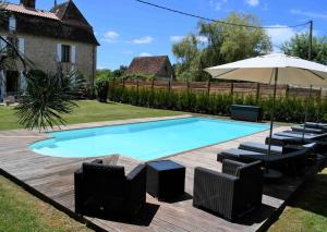 a swimming pool with chairs and an umbrella at La Marcillande in Saint-Cyprien