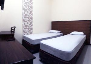 a bedroom with two beds and a table and a chair at Hotel Pelangi Indah in Semarang