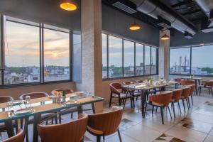 ein Restaurant mit Tischen und Stühlen und großen Fenstern in der Unterkunft THE M HOTEL in Raipur
