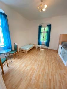 a living room with a wooden floor and blue curtains at Penzion Hřensko in Hřensko