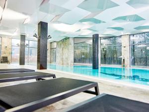una piscina con mesas y ventanas en un edificio en VacationClub – Diune Apartament 60, en Kołobrzeg