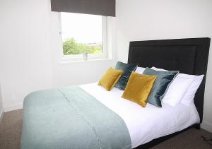 a bedroom with a bed with yellow and blue pillows at The Elm @ Short Stays in Basingstoke