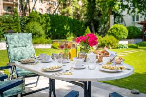 un tavolo bianco con piatti di cibo e fiori di Hotel Arcus Garden a Bratislava