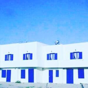 a white building with blue windows on it at Vigles in Adamas