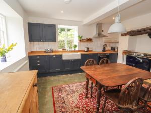 a kitchen with blue cabinets and a wooden table at Cwmalis Hall in Llangollen