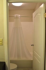 a white shower curtain hanging in a bathroom at Opal Hotel & Suites in Orlando