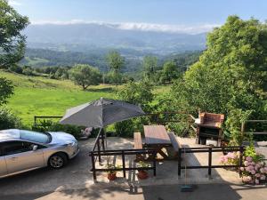 a table and chairs with an umbrella and a car at Casa Elena in Arriondas