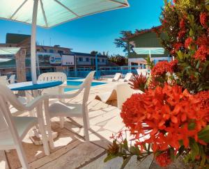 a patio with a table and chairs and flowers at Pousada Mar E Mata in Guarapari