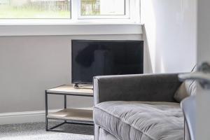 a living room with a couch and a television on a table at Trinidad House in East Kilbride