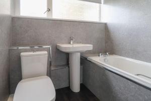 a bathroom with a toilet and a sink and a bath tub at Trinidad House in East Kilbride
