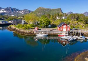 un puerto deportivo con barcos y una casa roja y montañas en Lofoten sommerhotell og vandrerhjem en Kabelvåg