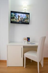 a white desk with a chair and a tv on the wall at Hotel Avenida in Benidorm
