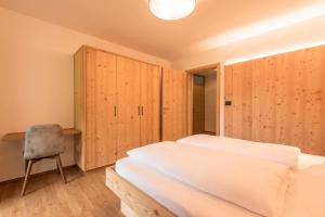 um quarto com armários de madeira, uma cama e uma cadeira em Apt Mirko - Haus Kostner em Santa Cristina in Val Gardena