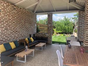 eine Terrasse mit Sofas, Tischen und Ziegelwand in der Unterkunft Casa Mediterana in 2 Mai