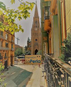 um grande edifício com uma torre de relógio em uma cidade em Pensión La Perla em San Sebastián