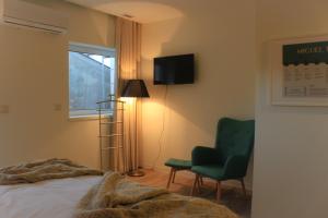 a bedroom with a bed, chair and television at Novabila Guesthouse in Vila Real