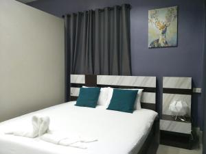 1 dormitorio con 2 camas y almohadas blancas y azules en Betong Cozy Guesthouse เบตง โคซี่ เกสต์เฮาส์, en Betong