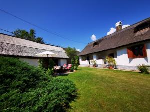 a house with a yard with chairs and an umbrella at Country house Balaton in Paloznak