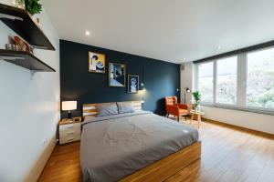 1 dormitorio con cama y pared azul en Aimee House - Phan Bội Châu en Hanói