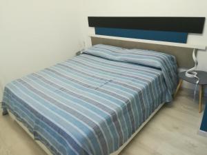 a bed with a blue and white striped comforter in a bedroom at 6 stelle e relax...nientaltro in Noli