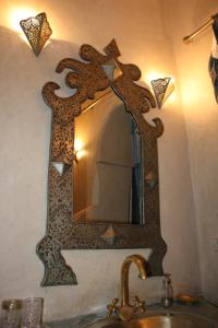 een spiegel aan een muur boven een wastafel bij Riad Lorsya in Marrakesh