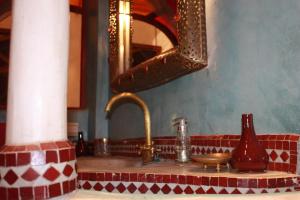 een wastafel in de badkamer met een koperen kraan en een spiegel bij Riad Lorsya in Marrakesh