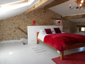 una camera con un letto rosso e una parete in pietra di 38 Friaudour a Saint-Pardoux