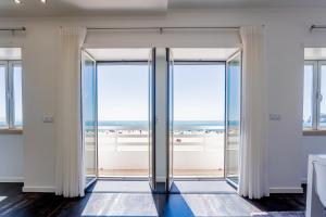 an open glass door with a view of the ocean at T4 Luís in Nazaré
