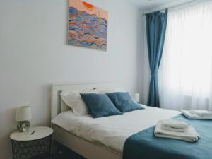 sypialnia z łóżkiem z niebieskimi poduszkami i oknem w obiekcie Promenada Apartment w Konstancy