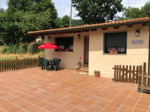 ein Haus mit einer Terrasse und einem roten Regenschirm in der Unterkunft Camiño á casa. in Ribadavia