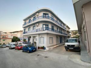 a building with cars parked in a parking lot at Blue Sky Apartments in Karpathos