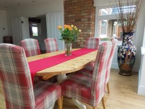 - une table à manger avec des chaises et un vase fleuri dans l'établissement Grooms Cottage, à Horncastle